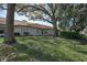 Well-maintained backyard with lush lawn and mature trees, showcasing serene outdoor living space and curb appeal at 9713 Sweeping View Dr, New Port Richey, FL 34655