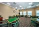 Bright game room with carpeted floors, multiple tables with green tops, and seating for recreational activities at 9713 Sweeping View Dr, New Port Richey, FL 34655