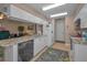 Galley kitchen featuring granite countertops, white cabinetry, stainless steel dishwasher, and tile flooring at 9713 Sweeping View Dr, New Port Richey, FL 34655