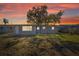Large backyard with a sunset in the sky with a door and chainlink fence at 10841 Scenic Dr, Port Richey, FL 34668
