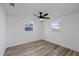 Well-lit bedroom with wood-look floors and two windows with a ceiling fan at 10841 Scenic Dr, Port Richey, FL 34668