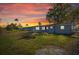 Single story home with a well-maintained lawn and sunset in the background at 10841 Scenic Dr, Port Richey, FL 34668