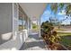 A long covered porch is lined with columns and windows. Croton plants are along the bottom of the columns at 10841 Scenic Dr, Port Richey, FL 34668