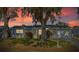 Beautiful home at dusk featuring a well-manicured lawn, mature trees and a cozy atmosphere at 10841 Scenic Dr, Port Richey, FL 34668