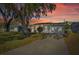 Home at sunset featuring a well-manicured lawn, mature trees and a paved drive at 10841 Scenic Dr, Port Richey, FL 34668
