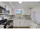 Modern kitchen with white cabinets, granite counters, stainless appliances at 10841 Scenic Dr, Port Richey, FL 34668