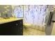 Bathroom featuring dark vanity with modern sink and mirror, plus a shower with a patterned curtain at 11817 Bayonet Ln, New Port Richey, FL 34654