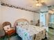 Well-lit bedroom with a floral quilt on the bed, decorative ceiling fan, and a stylish wicker chair at 13227 Molitor Ct, Hudson, FL 34669