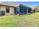 View of the exterior with an enclosed patio and grassy yard at 13227 Molitor Ct, Hudson, FL 34669