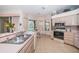 Bright eat-in kitchen with tile floors, stainless steel sink, and pass-through window to the dining and living area at 1528 Jutland Dr, Trinity, FL 34655