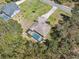 Aerial view of a home with a screened pool, surrounded by a lush tree canopy and a long concrete driveway at 18251 East Rd, Hudson, FL 34667