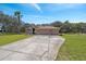 Inviting single-story home featuring a three-car garage, well-maintained lawn, and a palm tree-lined driveway at 18251 East Rd, Hudson, FL 34667