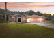 Charming single-story home with a three-car garage and a well-manicured lawn under a beautiful sunset sky at 18251 East Rd, Hudson, FL 34667