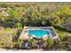 Aerial view of a community pool with chairs, tables and sunshades with mature landscaping at 215 Arbor Woods Cir, Oldsmar, FL 34677