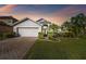 Beautiful single-Gathering home with lush landscaping, brick driveway, and two-car garage at sunset at 215 Arbor Woods Cir, Oldsmar, FL 34677
