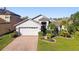 Charming single-story home with landscaped front yard, brick driveway, and attached two-car garage at 215 Arbor Woods Cir, Oldsmar, FL 34677