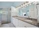 Bathroom featuring dual sinks with granite countertops, and a glass-enclosed shower at 2336 Edelweiss Loop, Trinity, FL 34655