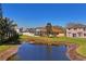 Scenic backyard pond view featuring a screened lanai and lush landscaping under a clear blue sky at 3042 Gianna Way, Land O Lakes, FL 34638