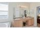 Bright bathroom featuring double sinks, a large mirror, and a separate tub at 3042 Gianna Way, Land O Lakes, FL 34638