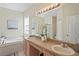 Bathroom view showcasing double sinks and a soaking tub under a bright window at 3042 Gianna Way, Land O Lakes, FL 34638