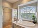 Bright bathroom with a large window, tub, and walk-in shower with glass door at 3733 Wiregrass Rd, New Port Richey, FL 34655