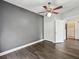 A simple bedroom offers dark laminate flooring, a ceiling fan, and ample closet storage at 3733 Wiregrass Rd, New Port Richey, FL 34655