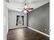 Bedroom with wood-look floors, ceiling fan, and a large window with blue curtains at 3733 Wiregrass Rd, New Port Richey, FL 34655