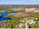 Beautiful aerial view of the property, pool, and fire pit surrounded by lush greenery and serene lakes at 3733 Wiregrass Rd, New Port Richey, FL 34655