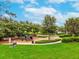 A well-maintained community playground with lush landscaping, benches, and a walking path at 3733 Wiregrass Rd, Trinity, FL 34655