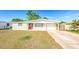 Charming single-story home featuring a red front door and an extended driveway leading to the garage at 4938 Fruitwood Loop, Holiday, FL 34690