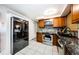 Functional kitchen with a stainless steel refrigerator and oven, complemented by wood cabinets and granite counters at 4938 Fruitwood Loop, Holiday, FL 34690