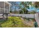 Large backyard with a white privacy fence, green grass, and various plants and trees at 513 Meres Blvd, Tarpon Springs, FL 34689