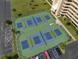 Aerial view of tennis courts with vibrant blue and green surfaces, nestled next to condos and parking at 5915 Sea Ranch Dr # 211, Hudson, FL 34667
