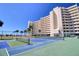 Low-angle of tennis courts and the condo building, complete with ocean views and palm trees at 5915 Sea Ranch Dr # 211, Hudson, FL 34667