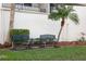 Outdoor seating area with two benches, small table, palm tree, and landscaping at 6035 Sea Ranch Dr # 408, Hudson, FL 34667