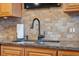 Kitchen sink features a modern black faucet, tan tile backsplash, and granite counters at 6035 Sea Ranch Dr # 408, Hudson, FL 34667