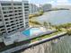 Aerial view of a condo community swimming pool with lounge chairs alongside beautiful bay views at 6035 Sea Ranch Dr # 408, Hudson, FL 34667