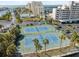 Aerial showcases community tennis courts near white condos, parking, and lovely bay views at 6035 Sea Ranch Dr # 408, Hudson, FL 34667