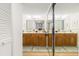 Elegant bathroom featuring double sinks, well-lit vanity, and mirrored sliding closet doors at 6035 Sea Ranch Dr # 411, Hudson, FL 34667