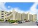 A multi-story building with parking and tropical landscaping under a partly cloudy sky at 6035 Sea Ranch Dr # 411, Hudson, FL 34667