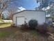 Exterior view of the property's shed, featuring a roll-up door, adjacent to some shrubbery at 6361 Boxwood St, Brooksville, FL 34602