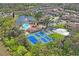 Expansive aerial view of a community with a pond, swimming pool, tennis courts, and lush greenery at 6440 Spring Flower Dr # 11, New Port Richey, FL 34653