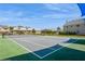 Outdoor community tennis court surrounded by fence and some residential houses at 6710 Devonshire Ln # 10A, New Port Richey, FL 34653