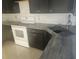 Modern kitchen with dark cabinetry, granite countertops, stainless steel sink, and white appliances at 7125 Silverwood Dr, New Port Richey, FL 34654