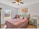 Bright bedroom with hardwood floors, ceiling fan and large window offering a serene view of the outdoors at 7205 Pinehurst Dr, Spring Hill, FL 34606
