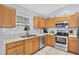 Well-equipped kitchen with stainless steel appliances, light wood cabinets, and tiled flooring at 7205 Pinehurst Dr, Spring Hill, FL 34606