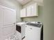 Well-lit laundry room featuring a washer, dryer, and storage cabinets for efficient organization at 7624 Red Mill Cir, New Port Richey, FL 34653