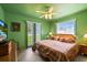 Cozy green bedroom with a ceiling fan, striped bedding, and natural light from two windows at 7901 Willow Brook Ct, Hudson, FL 34667