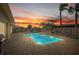Stunning backyard pool with a colorful sunset backdrop, framed by palm trees and patio furniture at 7901 Willow Brook Ct, Hudson, FL 34667