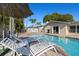 Relaxing pool area featuring lounge chairs, shade umbrella, and manicured landscaping at 7901 Willow Brook Ct, Hudson, FL 34667